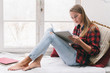 © ADDICTIVE STOCK - Reading young woman sitting near a window