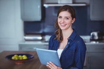 Poster - Beautiful woman using digital tablet in kitchen