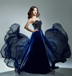 Woman in blue evening dress flying on wind. Young beauty woman i