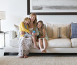 © Sam Diephuis/Blend Images - Caucasian mother and daughters using cell phone on sofa