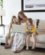 © Sam Diephuis/Blend Images - Caucasian mother and daughters using laptop on sofa