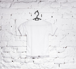 brick whitewashed wall with white t-shirt on hanger