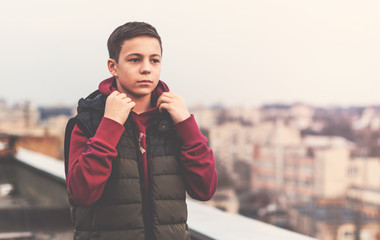 serious teenager sitting on the roof of the house