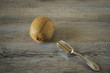 A kiwi with a silver spoon on a wooden table. Breakfast with fruit