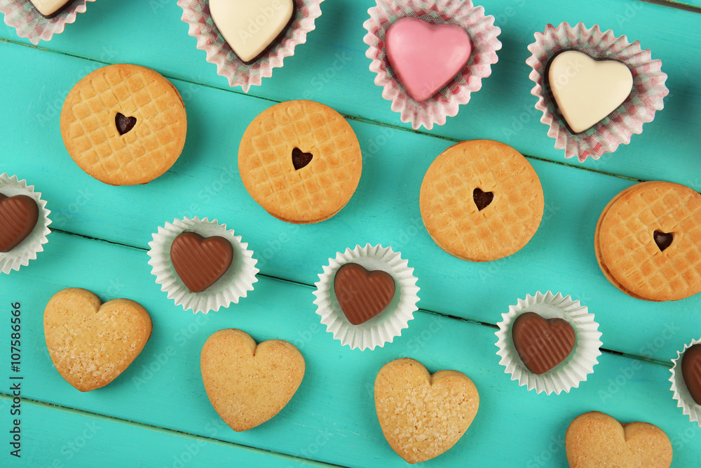 Valentine's Day concept. Composition of delicious chocolate candies and tasty cookies on turquoise wooden background