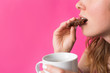 © creativefamily - Woman eating cookie with coffee in her hands