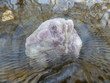 сиреневый камень флюорит в потоке холодной воде