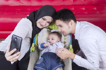 Wall Mural - Two parents and their baby taking selfie