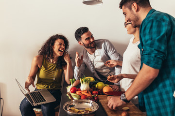 Young group of friends preparing vegetable meal and making fun.