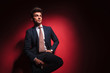 © Viorel Sima - businessman in black with red tie posing seated in studio