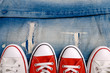White and red sneakers on a the ripped denim  background closeup.