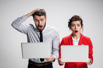 The young businessman and businesswoman with laptops  communicating on gray background