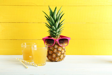 Wall Mural - Ripe pineapple with glasses of juice on a white wooden table