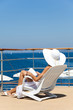 femme assise sur un transat sur une terrasse au bord de la mer