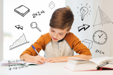 smiling student boy writing to notebook at home