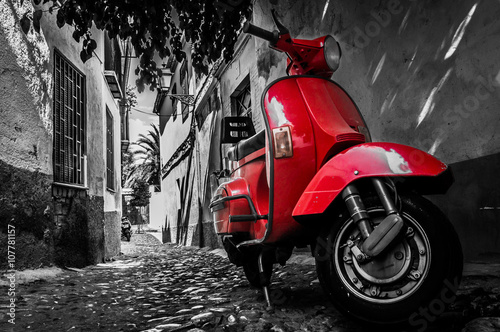 Fotografía A red vespa scooter parked on a paved street