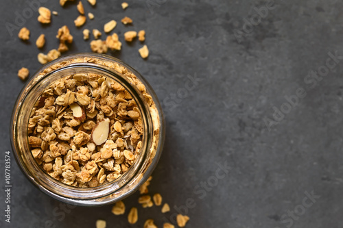 Cuadros en Lienzo Crunchy almond and oatmeal granola in jar, photographed overhead on slate with n