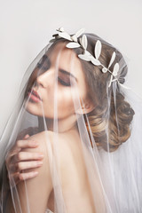 Beautiful bride with fashion wedding hairstyle - on white background.Closeup portrait of young gorgeous bride. Wedding. Studio shot.Beautiful bride portrait with veil over her face