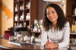 © DragonImages - Asian female bar owner standing behind counter and smiling at camera