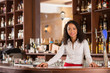 © DragonImages - Pretty smiling Vietnamese bartender standing behind counter