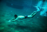 Fototapeta Tęcza - man swim underwater pool