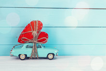 Background With Miniature Blue Toy Car Carrying A Heart On Blue