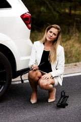 Wall Mural - Young woman holding jacke and wheel wrench