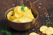 bowl of potato chips with dill on a dark background