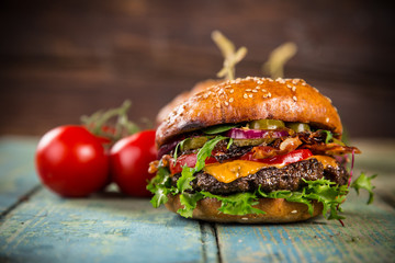 Tasty burgers on wooden table.