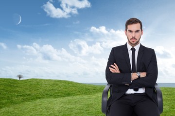 Poster - Composite image of serious businessman sitting with arms crossed