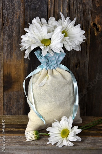 Fotografie, Obraz daisy bouquet in muslin bag on rustic wood
