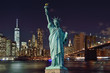 Manhattah skyline with Brooklyn Bridge at night and Statue of Liberty.