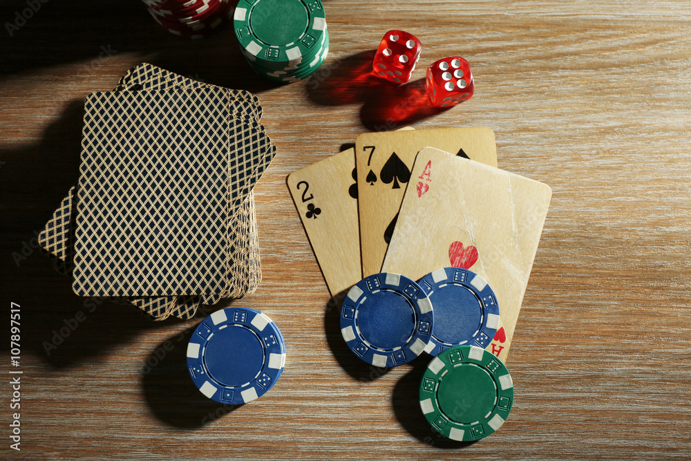 Set to playing poker with cards and chips on wooden table, top view