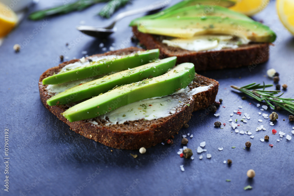Avocado sandwiches with spices on dark background