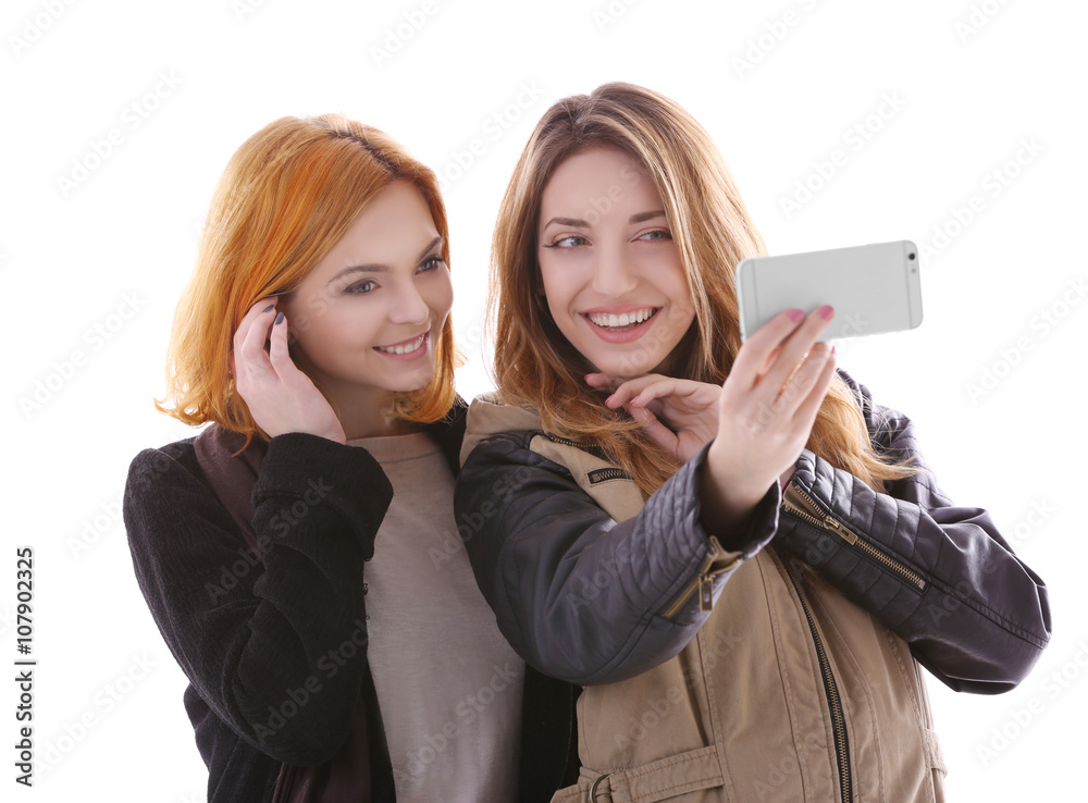 Two young women taking selfie in their winter clothes isolated on white