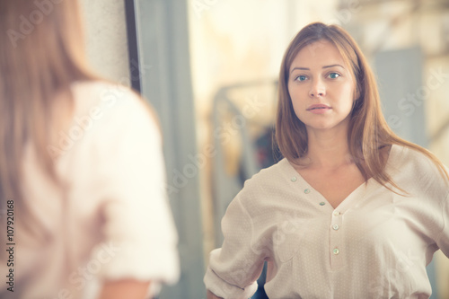 Fotografía Young woman looking in the mirror portrait in a shop