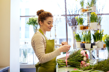 Wall Mural - smiling florist woman making bunch at flower shop