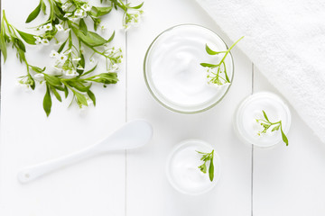 Herbal dermatology cosmetic hygienic cream with flowers skincare product in glass jar on white background