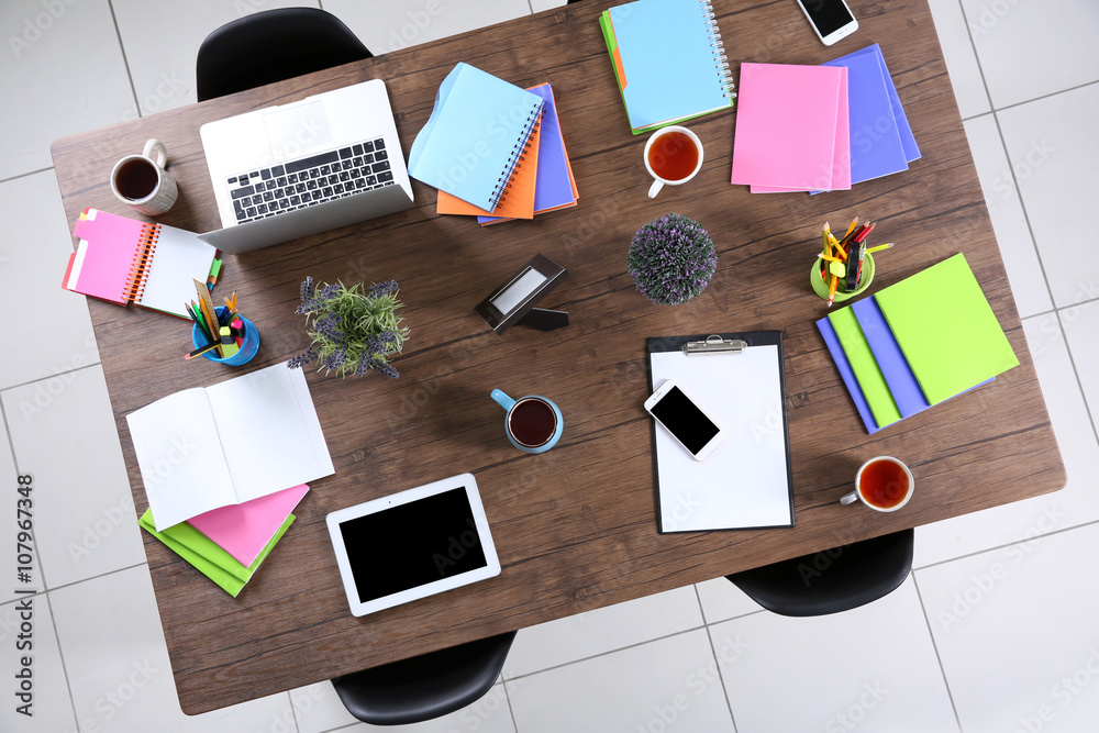 Session concept. Table with tablet, laptop, papers and cups of tea. Top view.