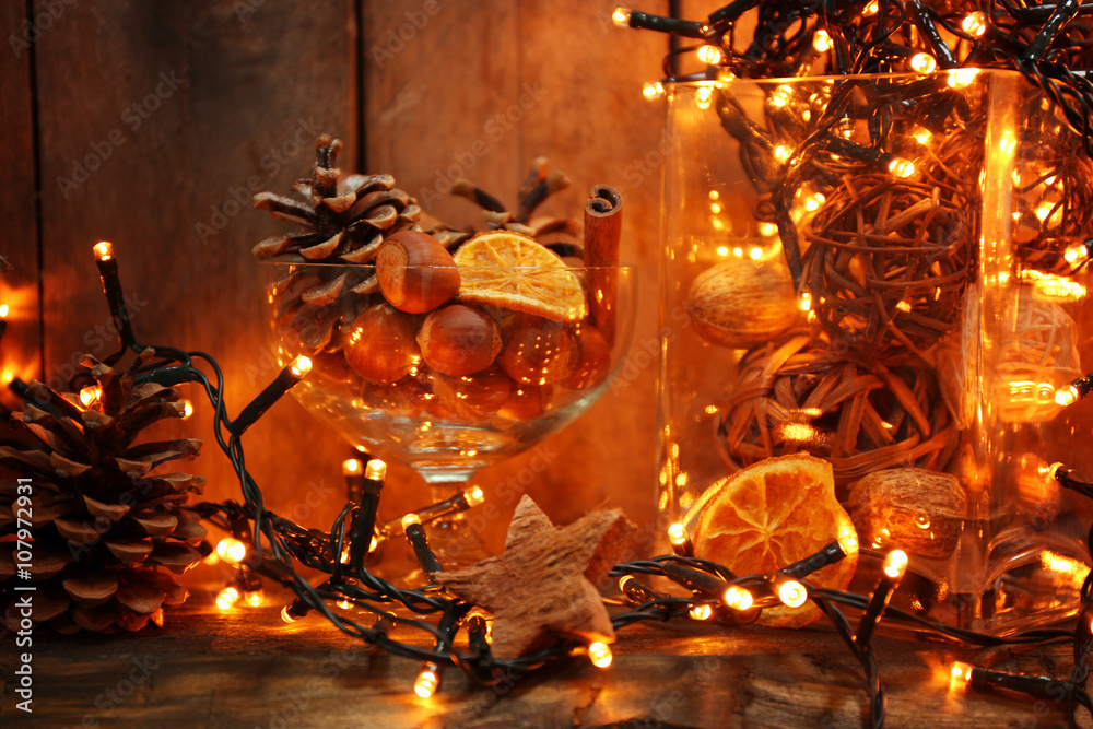 Electric garland with pine cones and hazelnuts on wooden background
