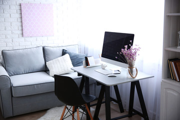 Canvas Print - Modern interior. Comfortable workplace. Wooden table with beautiful bouquet of flowers and computer on it.