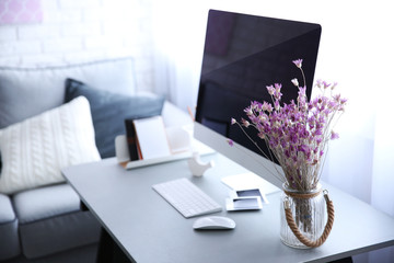 Canvas Print - Modern interior. Comfortable workplace. Wooden table with beautiful bouquet of flowers and computer on it, close up