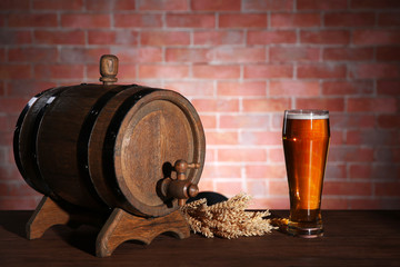 Wall Mural - Glass of light beer with wooden barrel and barley ears on brick wall background