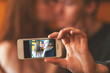 © lumenphotos - young couple kissing and photographing themselves on the phone