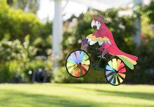 Toy Parrot On A Bicycle. Decorative Cockatoo On Wind Bike, Decoration For The Garden. 