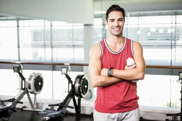 Wall Mural - Smiling man with arms crossed holding bottle of water