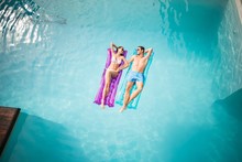 Happy Couple Relaxing On Inflatable Raft At Swimming Pool