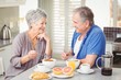 © WavebreakMediaMicro - Happy senior couple discussing while having breakfast