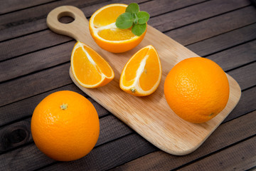 Freshly squeezed orange juice in glass, with fruits on wooden background