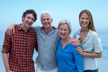 Wall Mural - Cheerful family by sea against blue sky